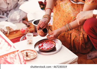 Indian bride washes nuts over the plate with species and petals