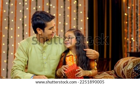 Indian brother gifting her cute little sister her rakhi gift - Raksha Bandhan concept, Indian Model . Brother gifts her sister a rakhi gift in the acceptance of her sisterly love - Indian customs