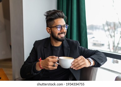 Indian Business Man In Black Suit Posed Indoor Cafe And Drinking Tea.