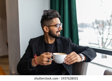 Indian Business Man In Black Suit Posed Indoor Cafe And Drinking Tea.