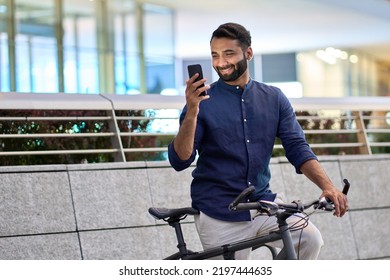 Indian business man holding smartphone using bike rental digital phone app scanning qr code to rent electric bicycle in city public eco transport mobile application standing on urban park on sunset. - Powered by Shutterstock