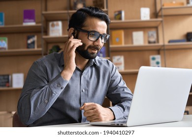 Indian business man professional employee, remote consultant, customer service support manager wearing headset talking at virtual meeting consulting client on video call at home office call center.