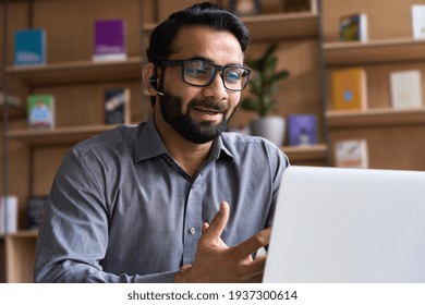 Indian business man speaking having virtual meeting on laptop. Professional remote online customer service support manager wearing headset talking consulting on video call at home office call center.