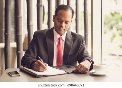 Indian Business Man Working With Document In Cafe