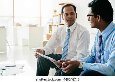 Indian Business People Discussing Information On Tablet Computer