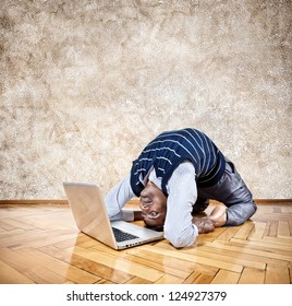 Indian Businessman Doing Yoga And Looking At His Laptop In The Office At Brown Textured Background