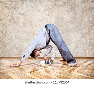 Indian Businessman Doing Yoga And Typing On His Laptop In The Office At Brown Background