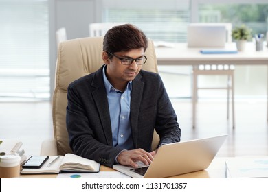 Indian Businessman In Glasses Reading Article On Laptop Screen