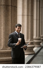 Indian businessman or Lawyer using a digital tablet outside a colonial courthouse building.  - Shutterstock ID 2386379087