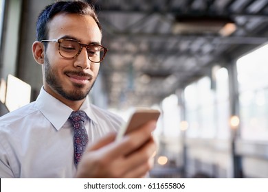 Indian businessman smiling confidently and surfing the net on a smartphone