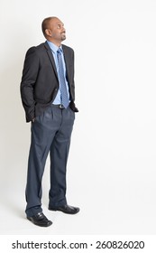 Indian Businessman Smiling And Looking Away Towards Copy Space, Full Body Standing On Plain Background.