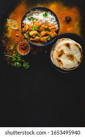 Indian Butter Chicken With Basmati Rice In Bowl, Spices, Naan Bread. Black Background. Space For Text. Butter Chicken, Traditional Indian Dish. Top View. Chicken Tikka Masala. Indian Cuisine 