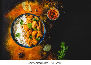 Indian Butter chicken with basmati rice in bowl, spices, black background. Space for text. Butter chicken, traditional Indian dish. Top view. Chicken tikka masala. Indian cuisine concept. Overhead