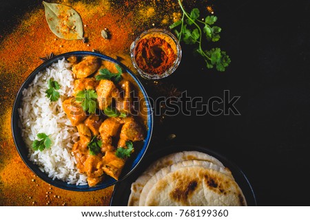 Indian Butter chicken with basmati rice in bowl, spices, naan bread. Black background. Space for text. Butter chicken, traditional Indian dish. Top view. Chicken tikka masala. Indian cuisine 