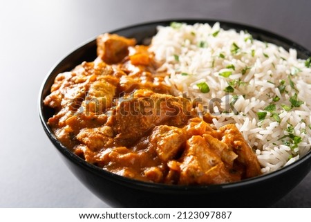 Indian butter chicken in black bowl on black background