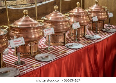 Indian Catering Lunch Buffet Consisting Of Tin Or Copper Brass Soup And Curry Bowls In Red Setting