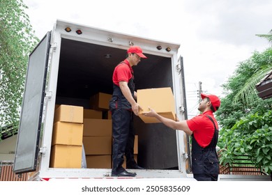 Indian and Caucasian partnership mover workers in red uniform uploading furniture and boxes to new house, shipping company small business owner using delivery truck sending packages to customers