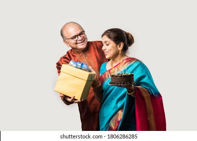 Indian Cheerful Old Couple Celebrating Birthday With Chocolate Cake While Wearing Ethnic Traditional Cloths