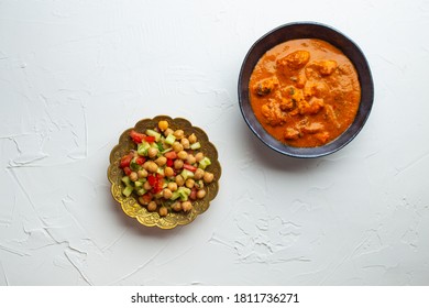 Indian Chicken Curry In Old Metal Bowl And Chickpea Salad With Vegetables On White Rustic Background. Traditional Indian Dish Butter Chicken Tikka Masala And Salad, Healthy Lunch Or Dinner. Top View
