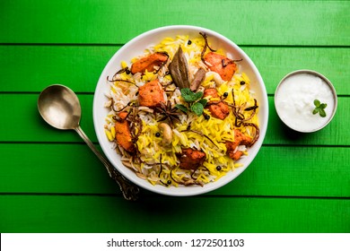 Indian Chicken Tikka Biriyani served in a bowl with yogurt. selective focus