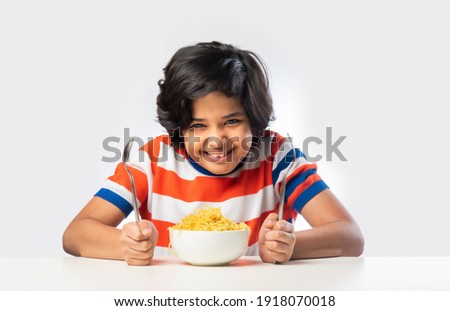 Indian child eating delicious noodles with Fork against White Background,  Asian boy eats Spaghetti in a bowl against white background