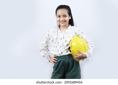 Indian City Kid Preparing Herself To Become A Future Engineer. The Girl Is Holding An Engineering Helmet Portraying Child Education And Grooming Concept.