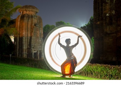 Indian classical male Odissi dancer posing against the backdrop of  Chitrakarini Temple, Bhubaneswar, Odisha. Light painting behind.