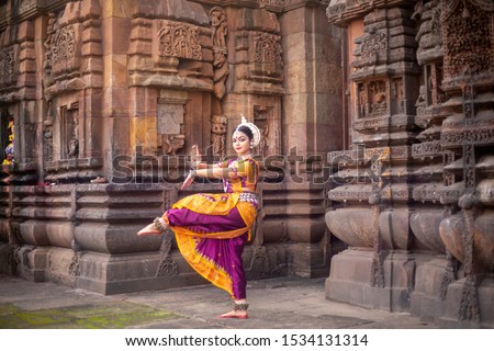 Indian classical odissi dancer at Brahmesvara Temple with sculptures in bhubaneswar, odisha, India