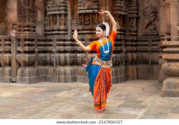 Indian classical Odissi dancer looks at the\
mirror during the Odissi dance recital against the backdrop of\
temple sculpture.art and culture of india.\

