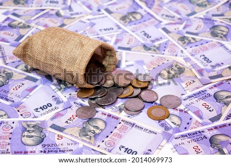 Indian coin stack to fall on Indian one hundred rupees background.