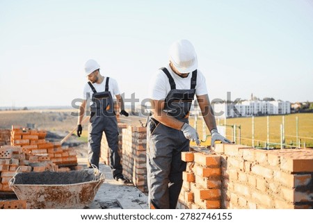 Indian construction workers work on the construction of a brick house. Construction of a brick wall.