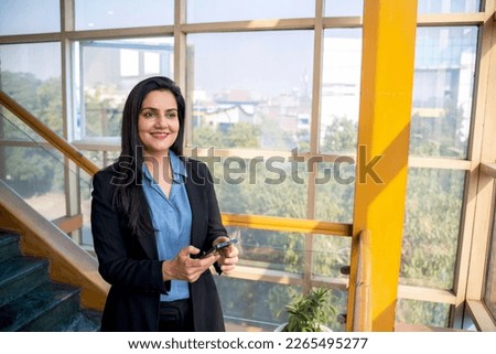 Indian corporate woman using smartphone at office.