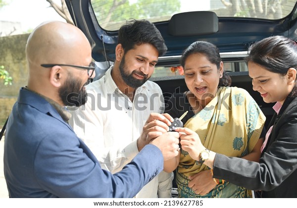 An\
Indian couple buying new car from the car\
dealer