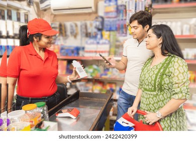 Indian couple at grocery store or supermarket using smart phone for digital payment. indian female cashier showing scan and pay qr code for payment digital india concept. - Powered by Shutterstock - Get 15% off with code: PIKWIZARD15