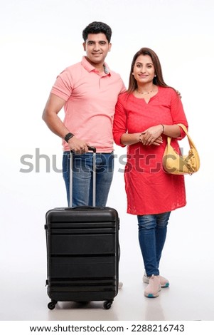 Indian couple holding trolly or suitcase bag in hand. Travel concept