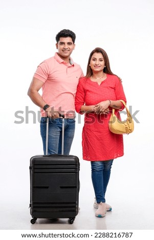 Indian couple holding trolly or suitcase bag in hand. Travel concept