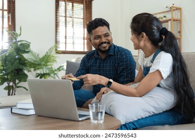 Indian Couple Managing Finances at Home, Paying Bills Online, and Planning Budget Together in a Modern Living Room Setting - Powered by Shutterstock