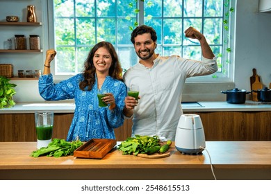 Indian couple preparing fresh green spinach juice together in kitchen, both showing strength gesture promoting health and fitness - Powered by Shutterstock