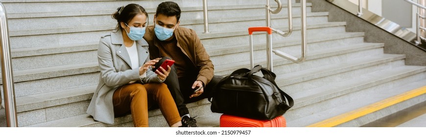 Indian Couple Wearing Face Masks Using Mobile Phone In Airport Indoors