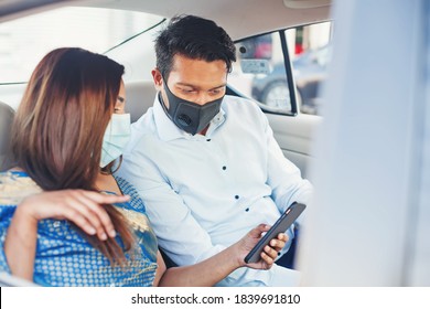 Indian Couple Wearing Face Medical Masks Taking A Cab And Using Mobile Phone App For Booking