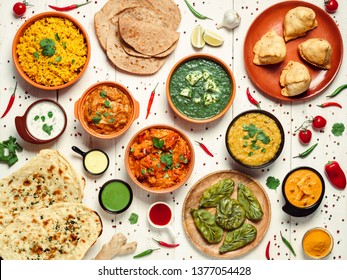 Indian cuisine dishes: tikka masala, dahl, paneer, samosa, chapati, chutney, spices. Indian food on white wooden background. Assortment indian pakistani meal top view or flat lay.