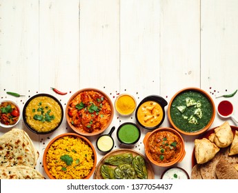 Indian cuisine dishes: tikka masala, dal, paneer, samosa, chapati, chutney, spices. Indian food on white wooden background. Assortment indian pakistani meal with copy space. Top view or flat lay