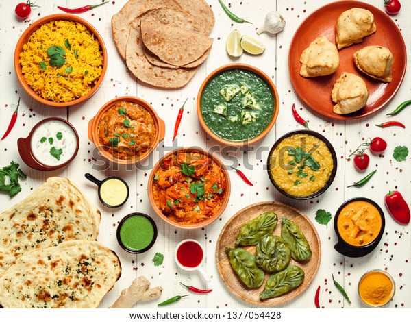 Indian\
cuisine dishes: tikka masala, dahl, paneer, samosa, chapati,\
chutney, spices. Indian food on white wooden background. Assortment\
indian pakistani meal top view or flat\
lay.