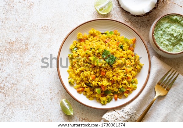 Indian cuisine Indian food. Indian cuisine. Poha or\
flattened rice traditional Western Indian breakfast with coconut\
chutney sauce curry leaves. national authentic vegetarian Asian\
food. top view