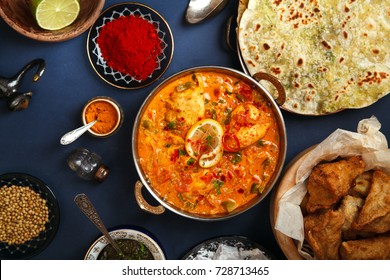 Indian cuisine on diwali holiday: tikka masala, samosa, patties and sweets with mint chutney and spices. Dark blue background