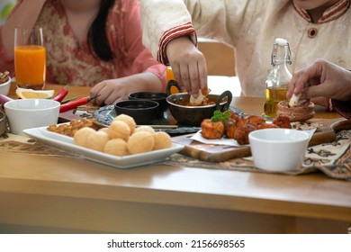 Indian Cuisine, Panipuri Is Snack From India, Curry Butter Chicken, Chicken Tikka, Biryani, And Naan Bread On Wooden Table, Boy And Girl Eating Indian Food, Using Hand