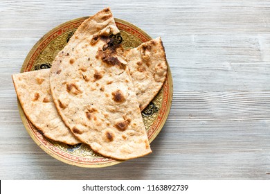 Indian cuisine - Tandoori Roti whole wheat flat bread on brass plate on gray table