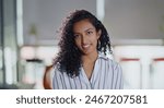 Indian curly hair young adult gen z smiling cute corporate girl standing proud look cam indoor office place. Confident happy business woman worker do pose head shot portrait video at job workplace