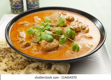 Indian Curry Lamb Rogan Josh In A Black Bowl, With Naan Bread.