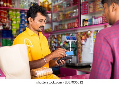 Indian customer making payment using credit card at groceries or Kirana shop - concept of digital or cashless payment, finance and Small business. - Shutterstock ID 2087036512